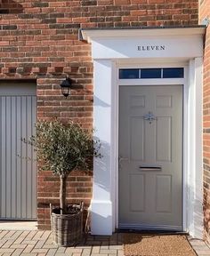 a grey door and potted plant in front of a brick building