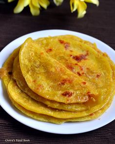 three yellow tortillas on a white plate with flowers in the backgroud