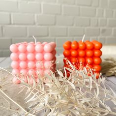 two orange and one pink balls are sitting next to each other on a table in front of a brick wall