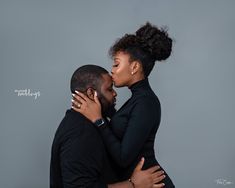 a man and woman embracing each other in front of a gray background