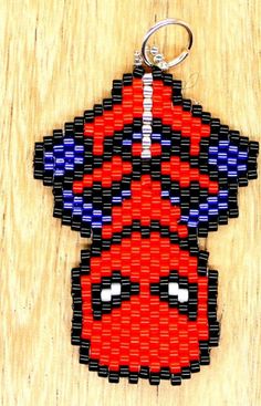 a red and blue beaded keychain hanging on a wooden surface