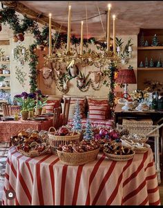 a table covered with baskets and food in front of a wall filled with christmas decorations