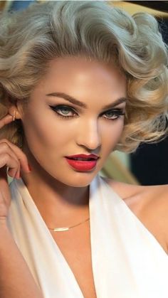 a woman with blonde hair and red lipstick posing for a photo in a white dress