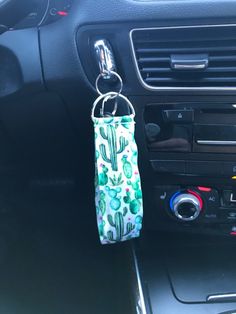 a keychain hanging from the center console of a car with cactus designs on it