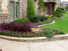 a flower bed in front of a brick house