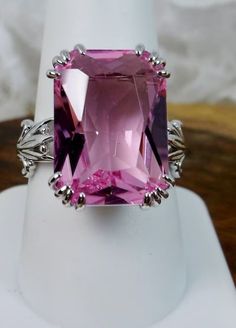 This is a brand new Victorian/Art Nouveau inspired in solid sterling silver. The gorgeous filigree ring is set with a 13ct Man-made/Simulated pink topaz. The rectangular cushion-cut gem is 18mm (just shy of 3/4th of an inch) by 13mm (1/2 inch) in size. The inside of the band is marked 925 for solid sterling. Notice the intricate and detailed leaf floral design of the silver filigree setting. A giftbox is included for safe keeping. Feel free to ask questions and thanks for looking at my listings. Sterling Silver Solitaire Gemstones For Anniversary, Silver Emerald Cut Gemstones With Accent Stones, Pink Sterling Silver Gemstones For Anniversary, Hallmarked Emerald Cut Topaz Ring In Sterling Silver, Pink Topaz Center Stone Ring In Sterling Silver, Pink Topaz Ring With Accent Stones In Sterling Silver, Pink Gemstone Ring, Pink Gemstones Ring, New Victorian