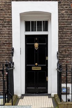 a black door with a gold handle on the side of a brick building in london