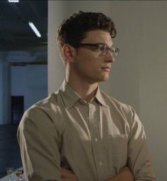 a man wearing glasses standing with his arms crossed