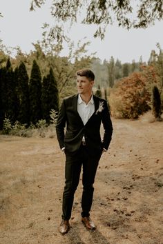 a man in a suit standing on a dirt road