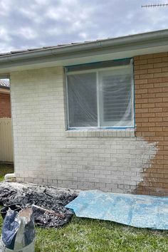 a house that has been painted white with blue tape on the windows and grass in front of it