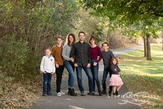 a family posing for a photo in the park with trees and grass on either side