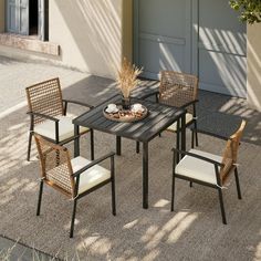 an outdoor dining table with chairs and a plate of food on the ground in front of a garage door