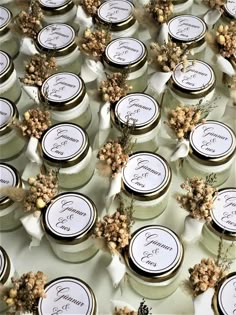 many small jars with labels on them sitting on a table covered in flowers and leaves