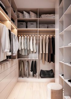 a walk in closet filled with lots of clothes and bags on top of white shelves