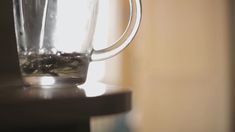 a blender filled with green liquid on top of a wooden table next to a window