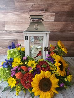 a lantern with sunflowers and other flowers around it