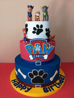 a three tiered cake with paw patrol characters on it's sides and paw prints on the top