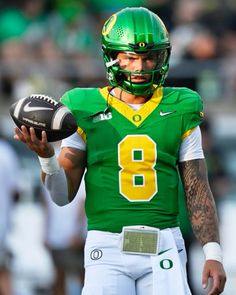 a man holding a football in his right hand and wearing a green uniform with the number 8 on it