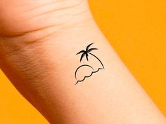 a small palm tree tattoo on the left inner arm and wrist is shown in black ink