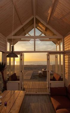 the inside of a house with wooden flooring and windows looking out at the ocean