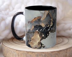 a black and gold marbled coffee mug sitting on top of a piece of wood