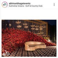 a couch sitting on top of a black and white checkered floor next to red flowers