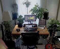 there is a desk with two laptops and a keyboard on it in front of a window