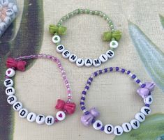 two bracelets with name beads and bows on them