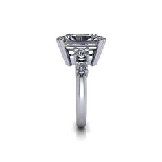 a white gold ring with an oval cut diamond in the center and side stones on each side