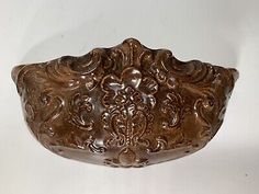 an ornately carved brown bowl on a white background