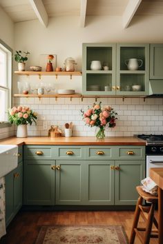 a kitchen with green cabinets and flowers in vases on the counter top, along with an area rug