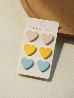 four heart shaped studs on top of a piece of paper next to a wooden tray