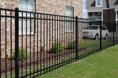 a car parked in front of a brick building behind a black fence with bars on it