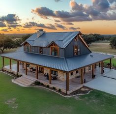 an aerial view of a large house in the middle of a grassy field at sunset