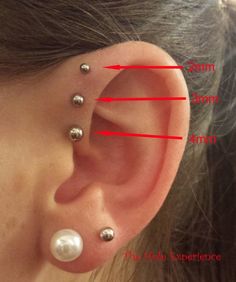 an ear with three different piercings on the top and two smaller ones behind it