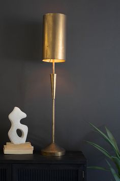 a gold lamp sitting on top of a table next to a white sculpture