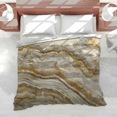 a bed in a bedroom with white walls and marbled comforter on top of it