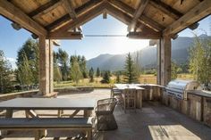 an outdoor kitchen and grill area with mountains in the background