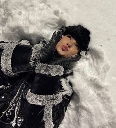 a doll is laying in the snow wearing black gloves