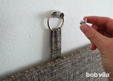 a hand holding a metal ring on the side of a curtain with rivets