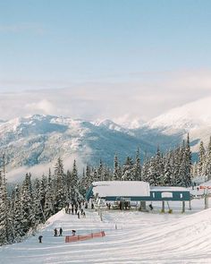 skiers and snowboarders at the bottom of a snowy slope with mountains in the background