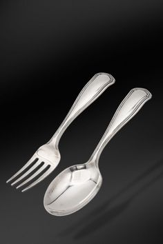 two forks and spoons on a black background with shadow from the fork to the left