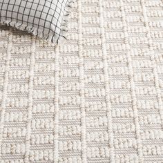 a close up view of a white carpet with black and white checkered pillows on it