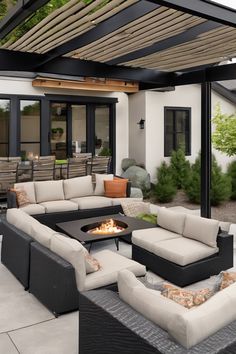 Modern outdoor patio with cushioned seating around a fire pit and a dining area in the background. Indoor Outdoor Extension, End Terrace Extension, Ipe Wood