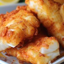 some fried food on a white plate with lemons in the backgroung