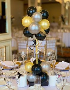 a table set up with black, white and gold balloons