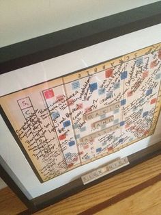 a framed map with writing on it in a wooden frame, sitting on top of a hard wood floor