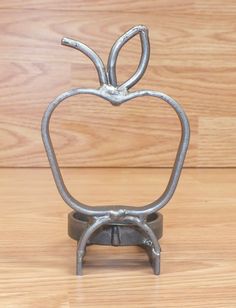 an apple shaped metal object sitting on top of a wooden table