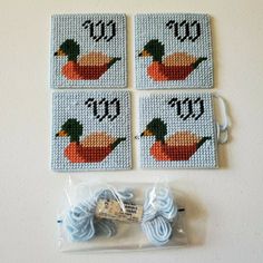 four cross stitch coasters with yarn and scissors