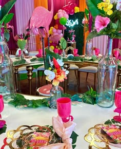 the table is set with flamingos and pink flowers in vases, plates, and napkins